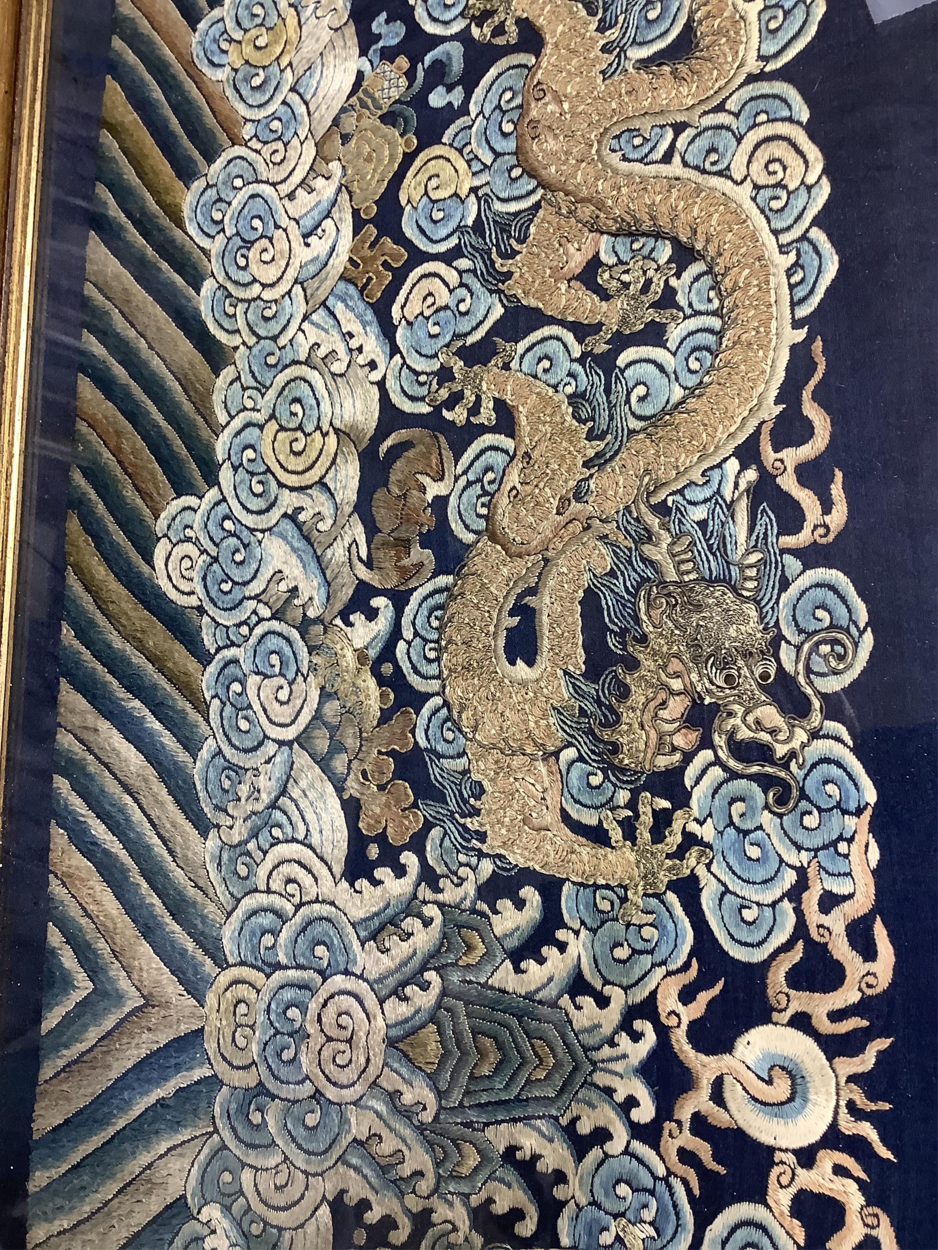 A framed late 19th / early 20th century Chinese silk embroidered five claw dragon panel from the base of a robe, 59cm wide x 23cm high. Condition - good, colours and embroidery strong
